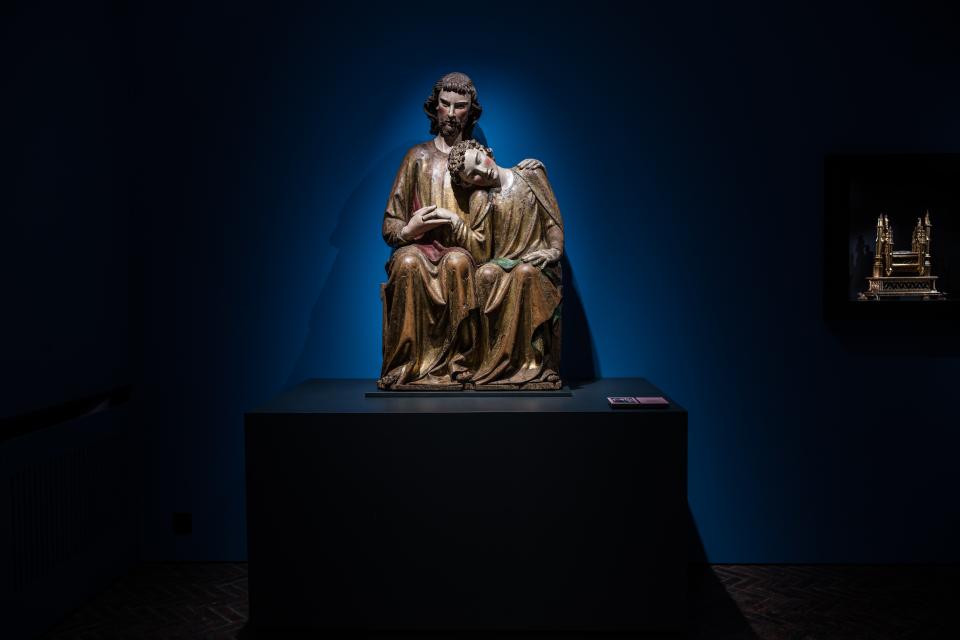 Een houten sculptuur van Johannes die zijn hoofd laat rusten op de schouder van Jezus.