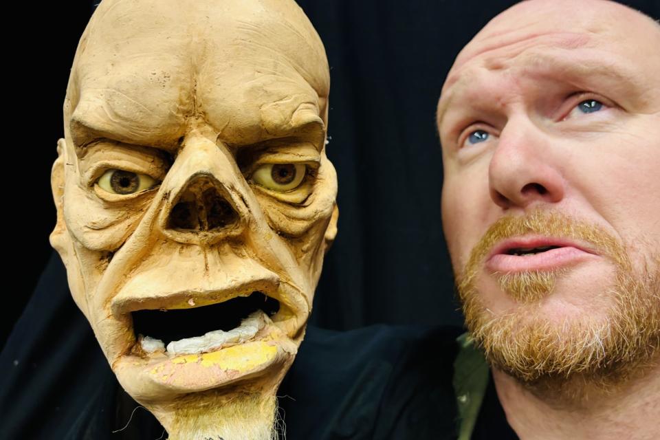 Het gezicht van een man naast het 'gezicht' van een pop, die hij in de hand houdt.